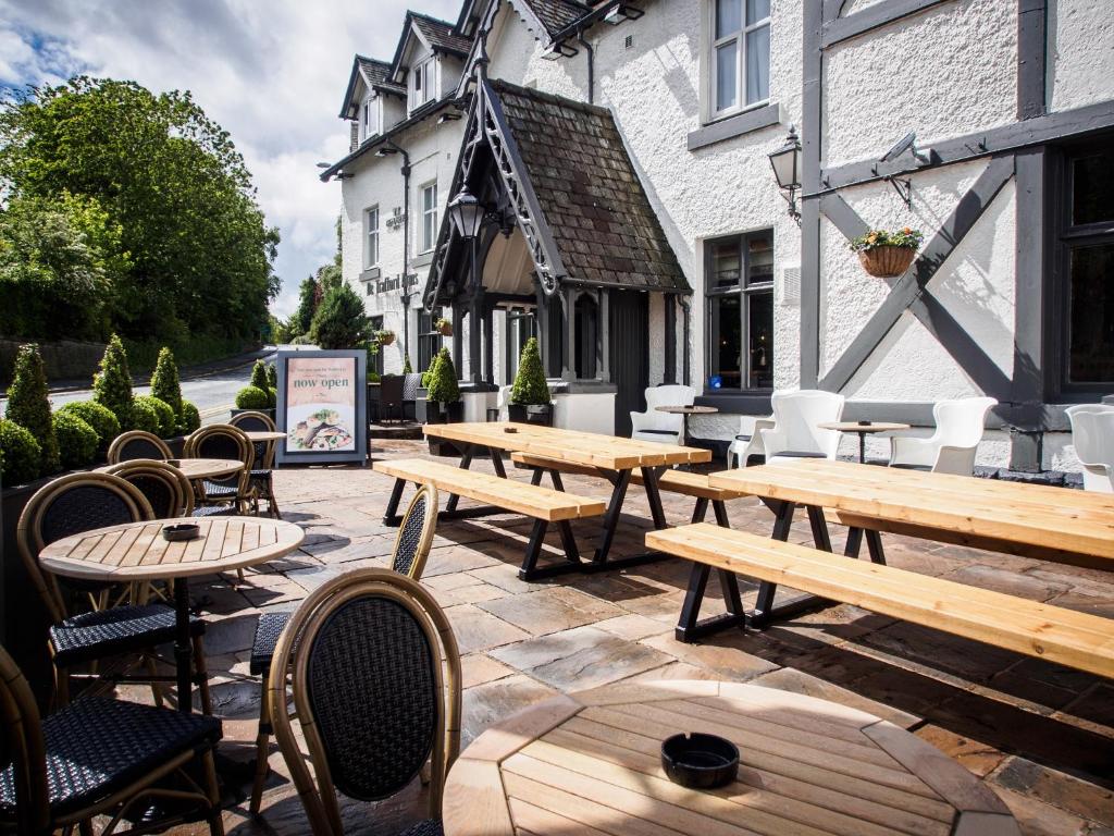 a patio with wooden tables and chairs in front of a building at De Trafford Arms by Chef & Brewer Collection in Alderley Edge