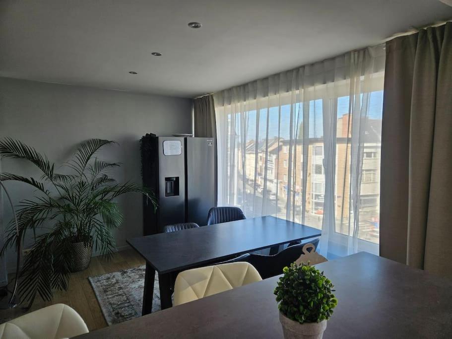Un comedor con una mesa y un gran ventanal. en Urban Comfort Mechelen, en Malinas