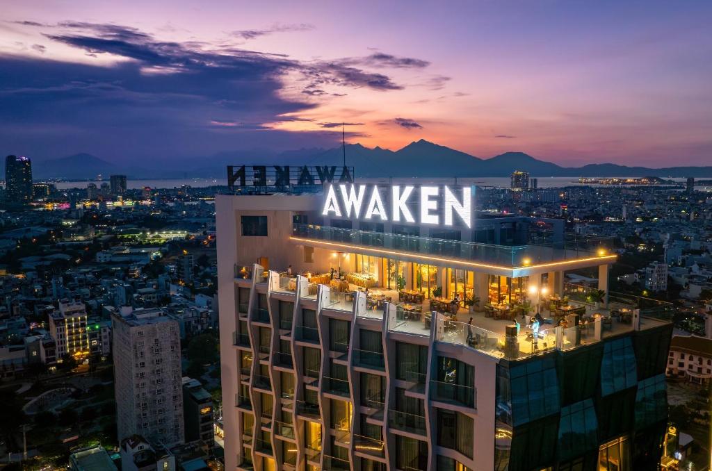 a building with a sign on top of it at night at Awaken Da Nang Hotel in Danang