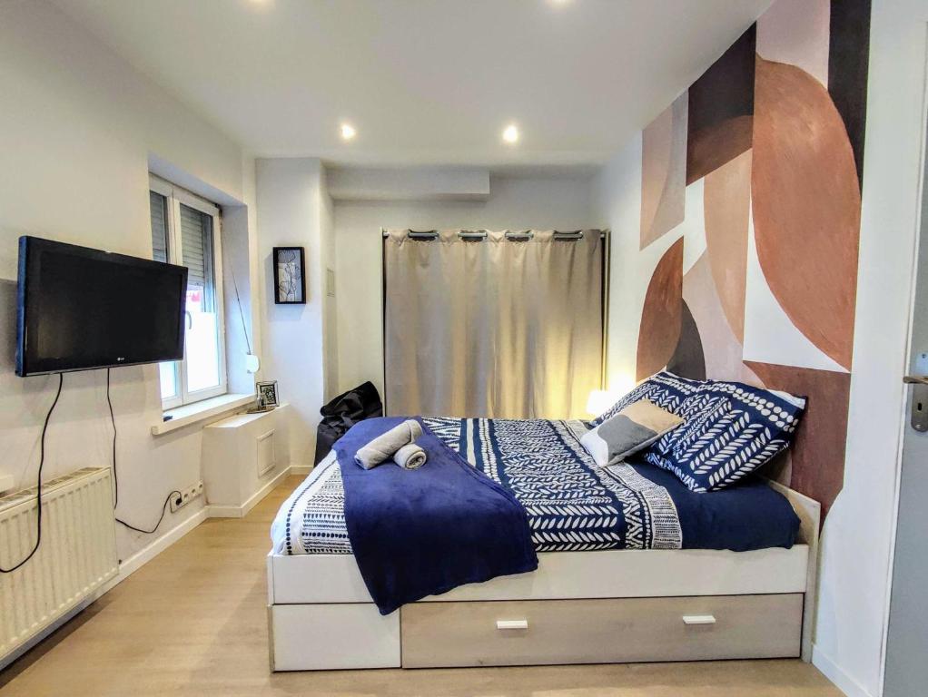 - une chambre avec un lit doté d'oreillers bleus et une télévision dans l'établissement Palais du Luxembourg, à Roubaix