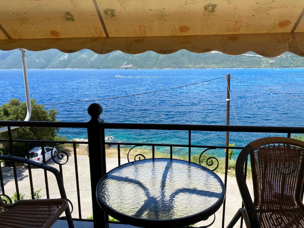 a table and chairs on a balcony with a view of the water at Studios&apartments Thomas in Vasiliki