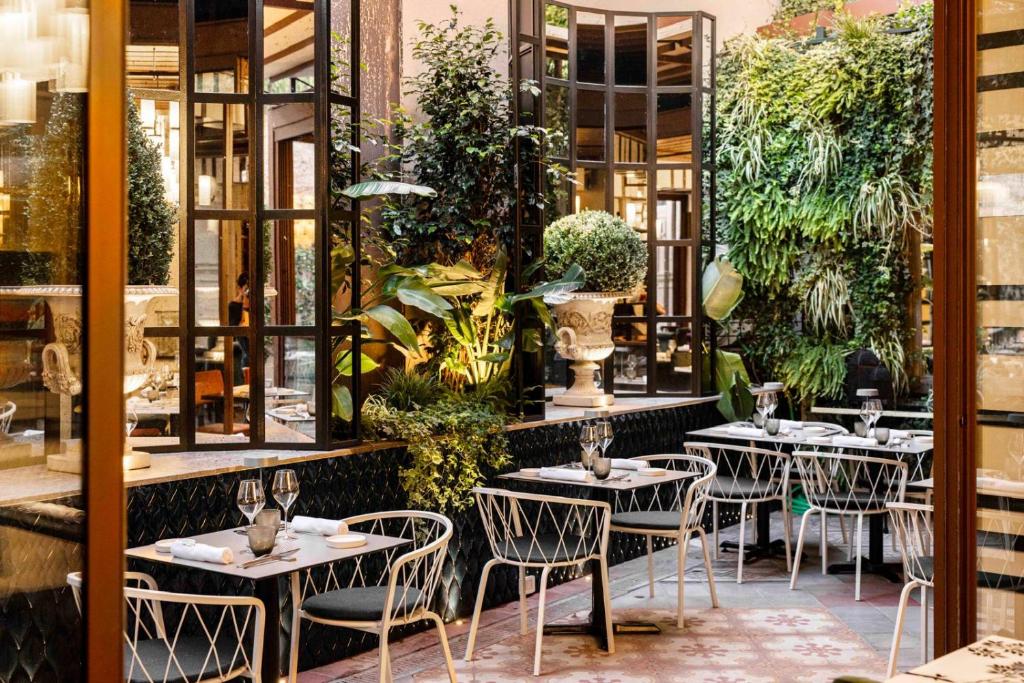a restaurant with tables and chairs and plants at Roma Luxus Hotel in Rome