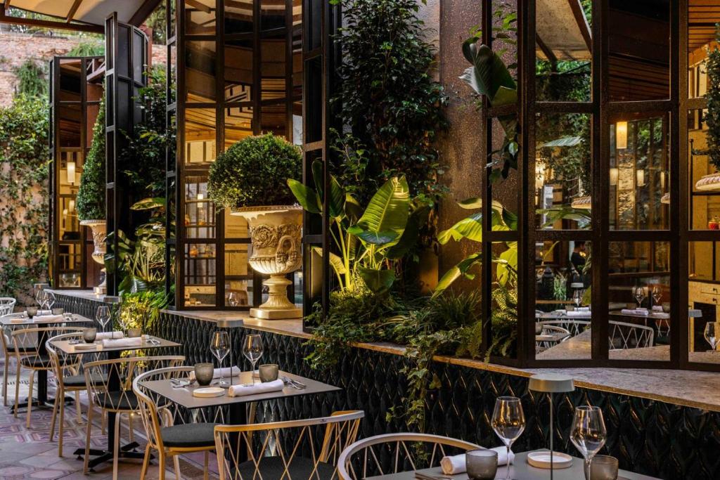 a restaurant with tables and chairs and plants at Roma Luxus Hotel in Rome