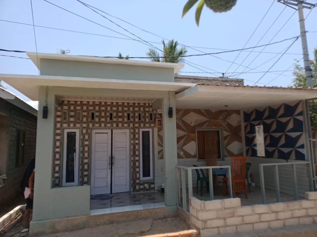 a small house with a white door and a porch at Waru Homestay Gili Gede in Gili Gede
