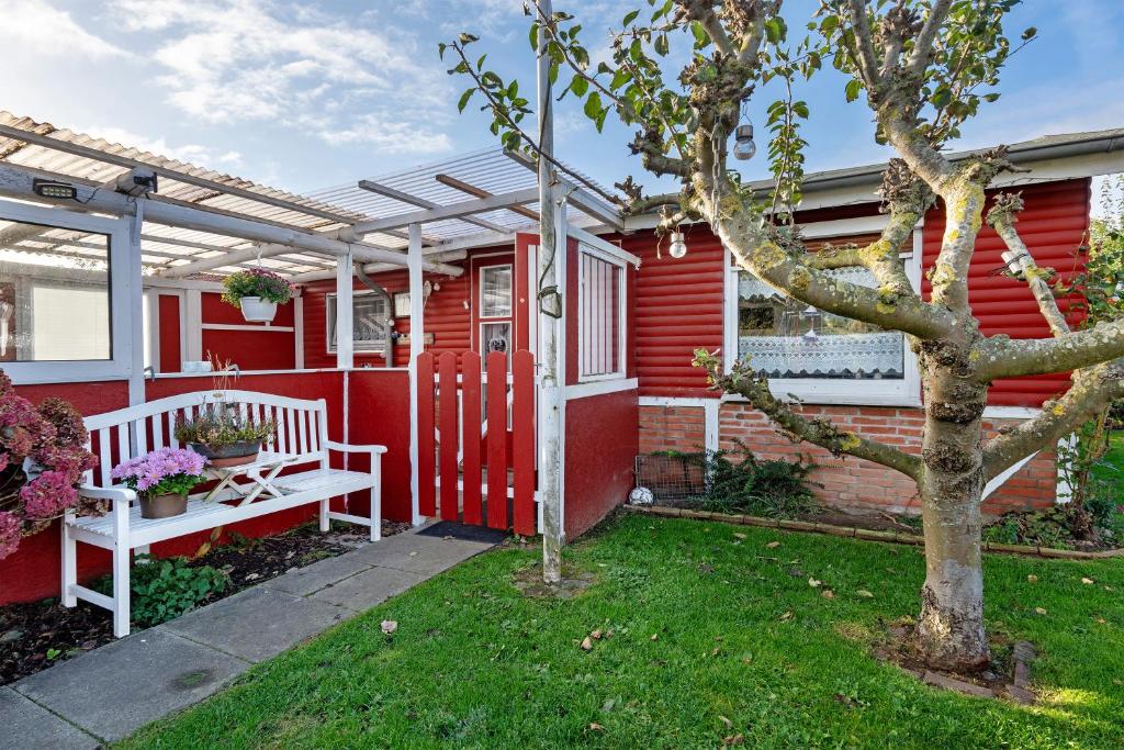 una casa roja con un banco blanco y un árbol en Ferienhaus Wallenstein, en Kappeln
