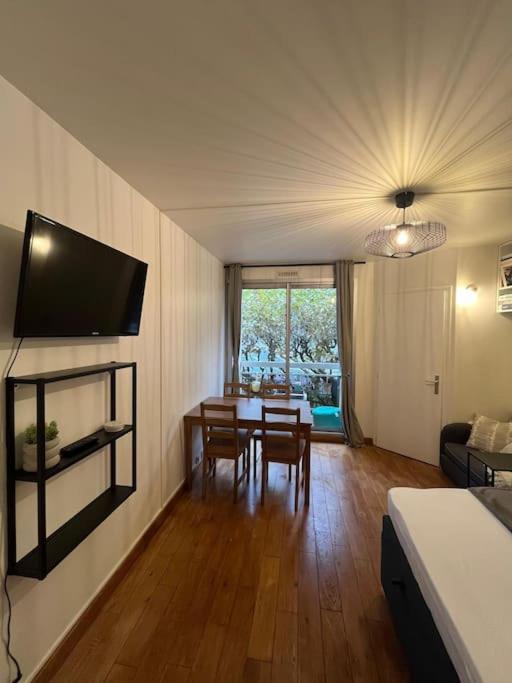 un salon avec une table et une télévision au mur dans l'établissement Porte de Paris Studio standing, à Vanves