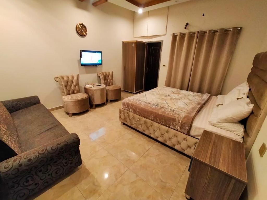 ein Schlafzimmer mit einem Bett, einer Couch und einem Fernseher in der Unterkunft HOTEL DAY IN Empouriem in Lahore