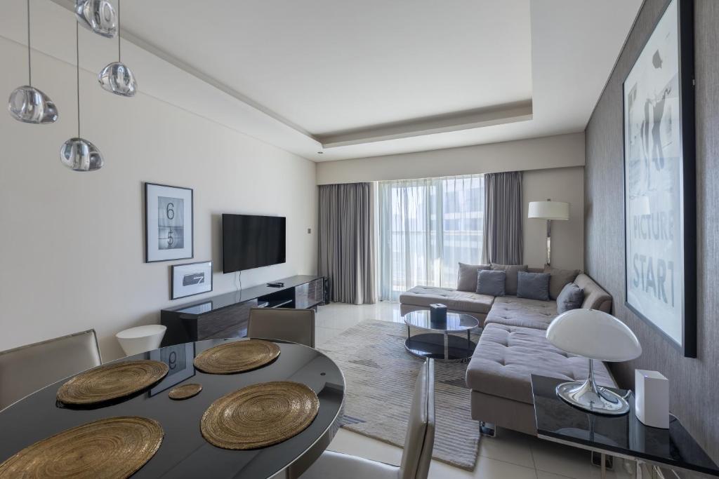 una sala de estar con un sofá y una mesa en Cozy 1BR with balcony great view, Damac Towers, en Dubái