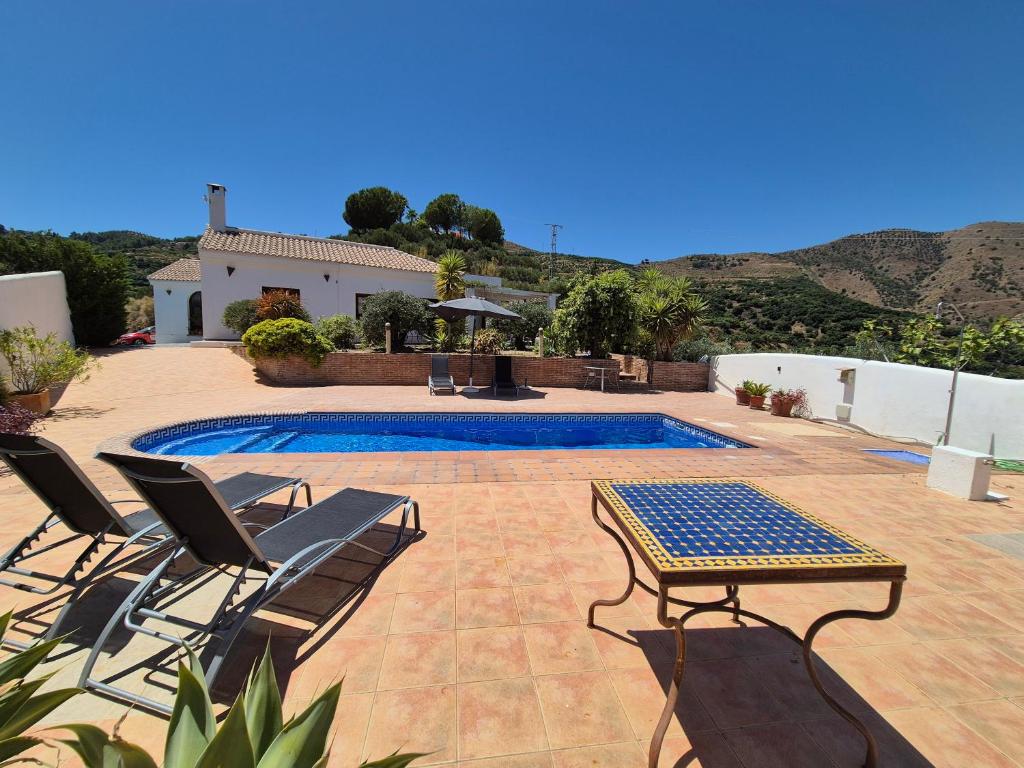 a swimming pool with chairs and a table next to a house at Casa Laura in Almuñécar