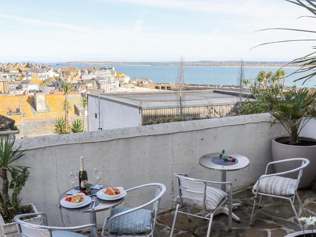 a patio with tables and chairs and a view of the ocean at Heron in St Ives