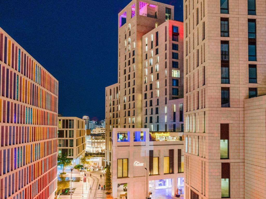 a group of tall buildings in a city at night at Alwadi Hotel Doha - MGallery Collection in Doha