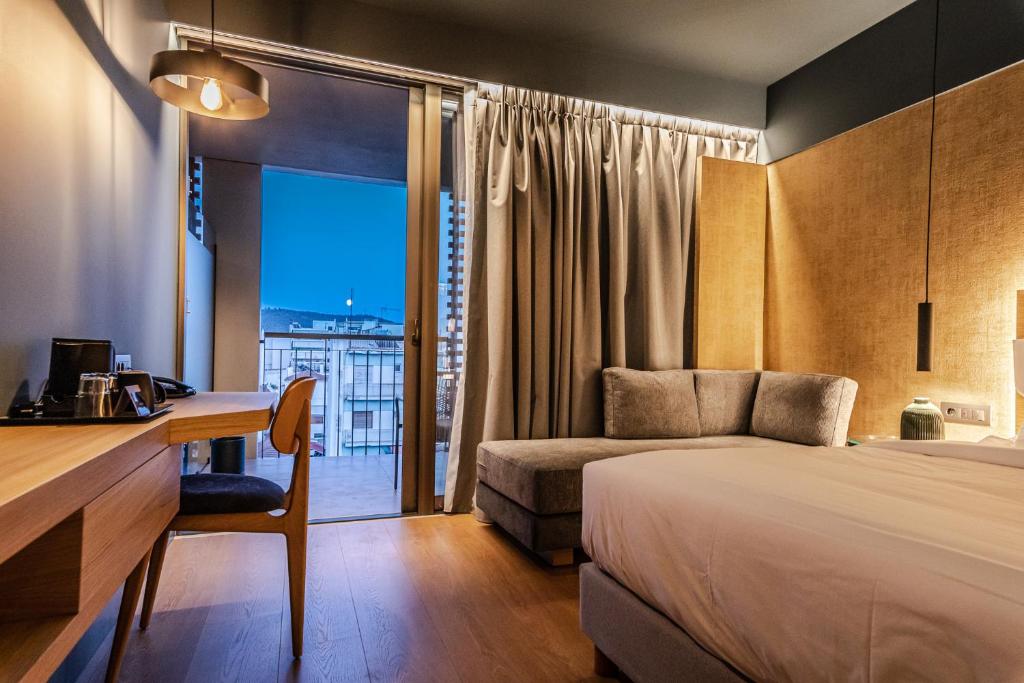 a hotel room with a bed and a desk and a window at Magnes Hotel in Volos