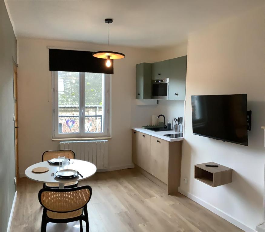 Il comprend un petit salon avec une table et une cuisine. dans l'établissement L'Echappée Polletaise Central Typique Wifi, à Dieppe
