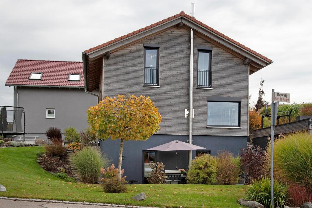 a gray house with a tree in the front yard at Kathi´s Allgäuliebe in Weitnau