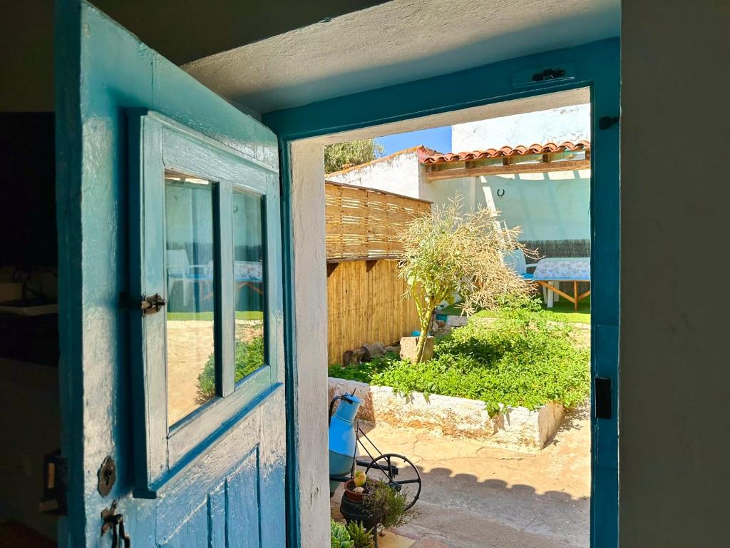 an open blue door with a view of a yard at Atelier 20th in Ervidel