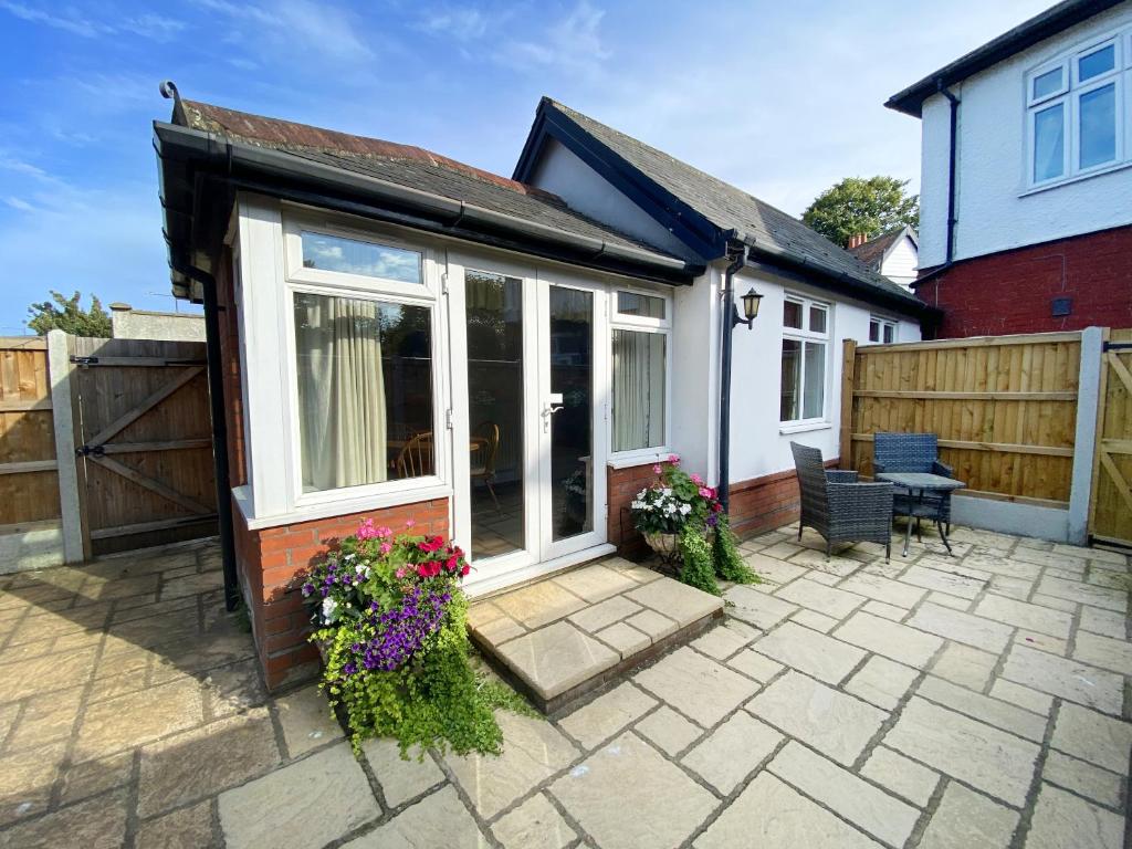 a house with a patio with flowers and a fence at Garden Cottage in Great Yarmouth