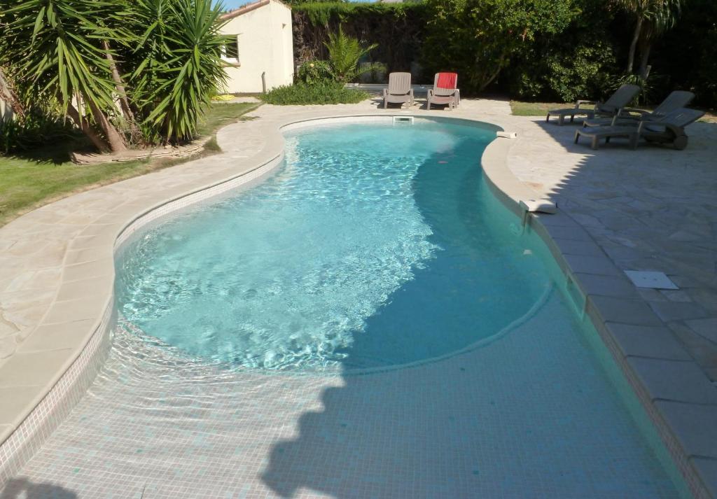 a swimming pool with blue water in a backyard at Superbe villa T4 classée 3 étoiles avec piscine privative chauffée 8PALCR in Saint Cyprien Plage