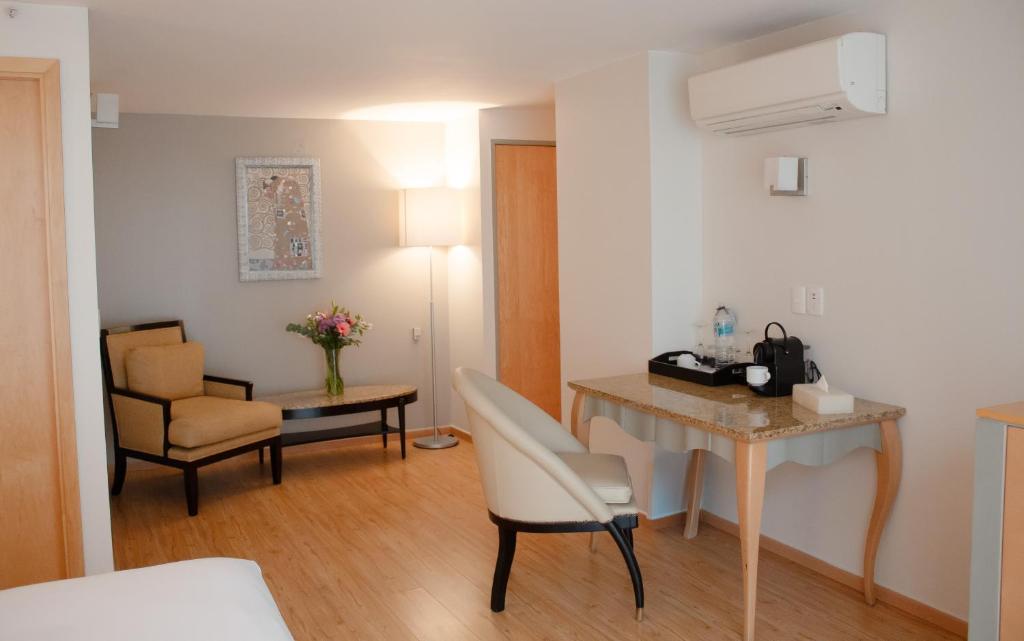 A sitting and work area with an armchair, desk, drinks station, and air conditioner.