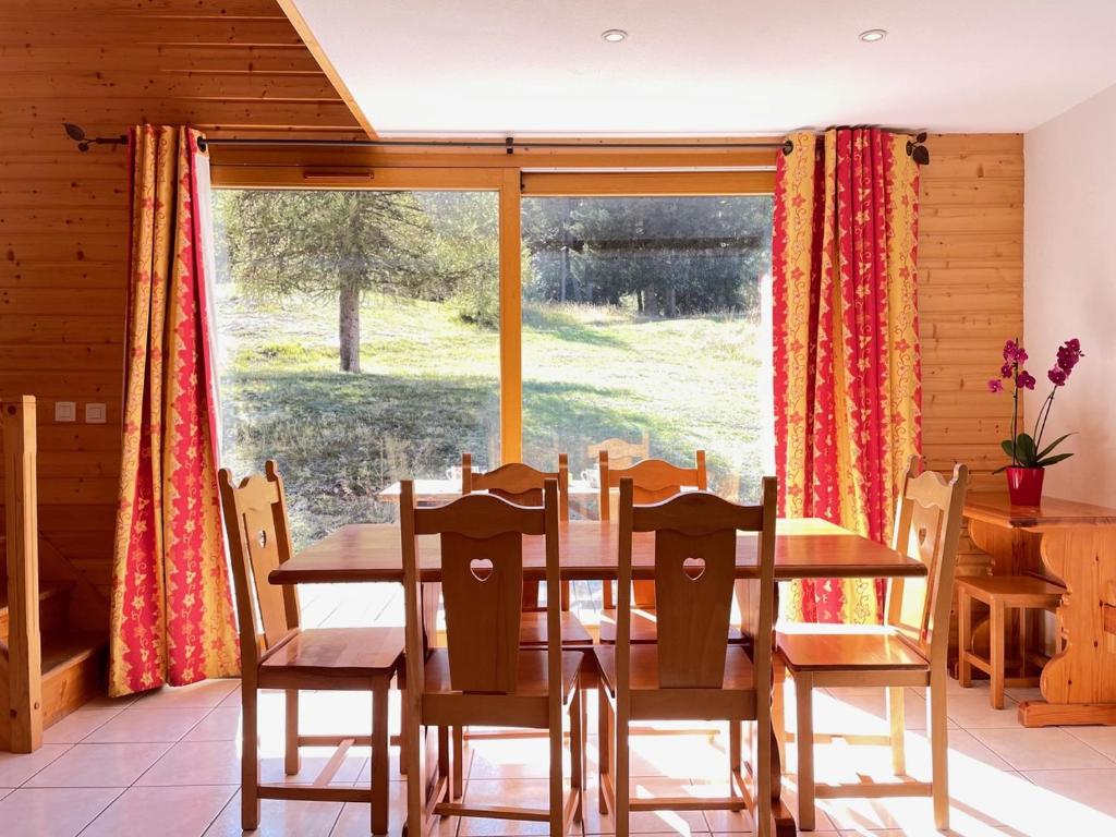 une salle à manger avec une table et des chaises et une grande fenêtre dans l'établissement Chalet Margot 20, à Saint-Étienne-en-Dévoluy