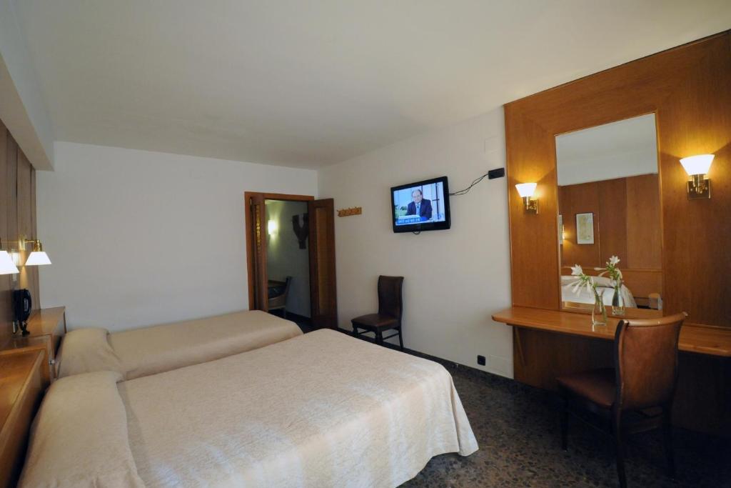 a hotel room with a bed and a desk and a television at Hotel Jaume I in Andorra la Vella
