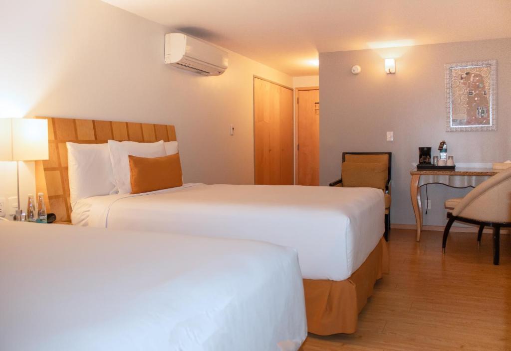 A two-bed room with a desk, drinks station, air conditioner, and armchair.