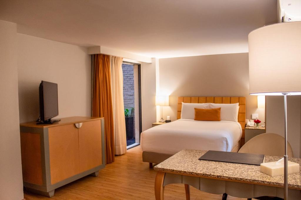 A large-bed room with a television cabinet, worktable, and narrow glazed opening.