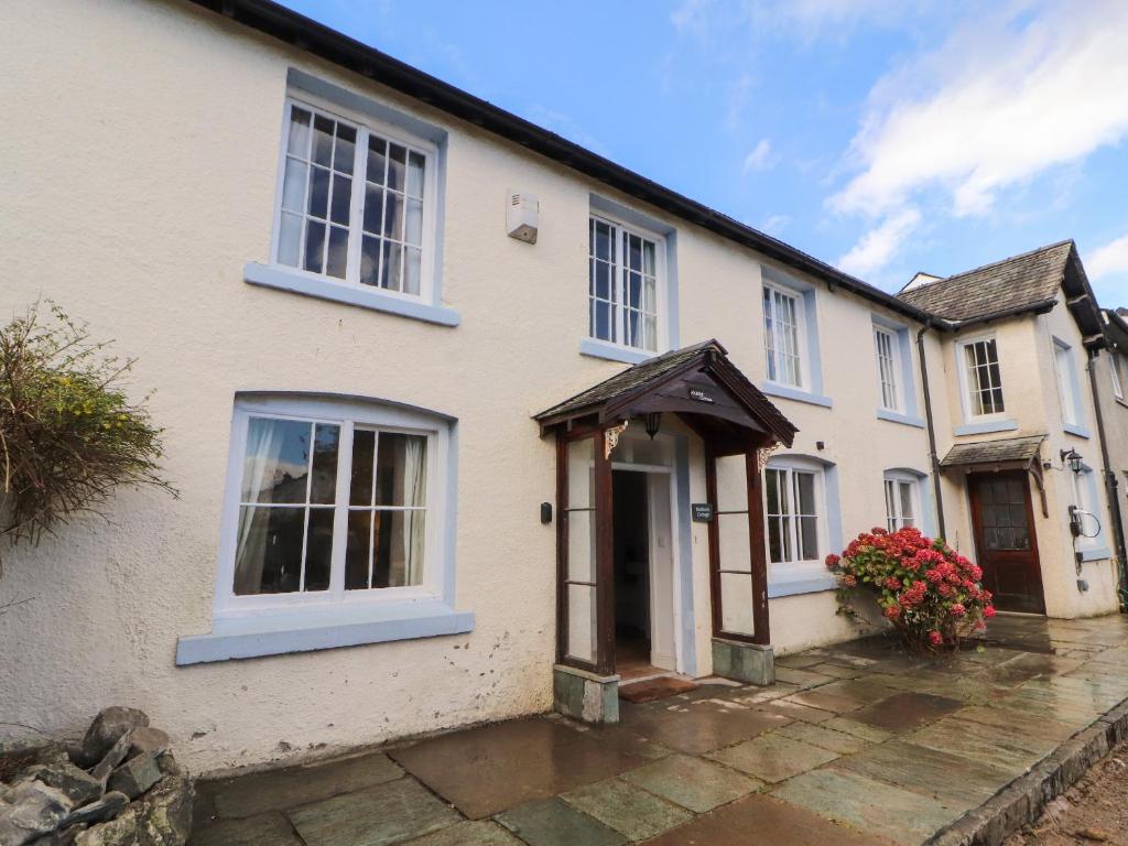 une maison blanche avec une porte et des fleurs devant dans l'établissement Holborn Cottage, Blencathra Street, à Keswick