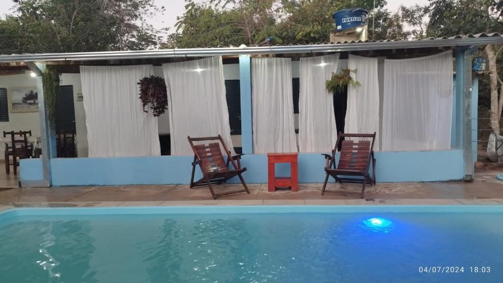 duas cadeiras e uma mesa ao lado de uma piscina em Chácara Liberdade em Pirenópolis