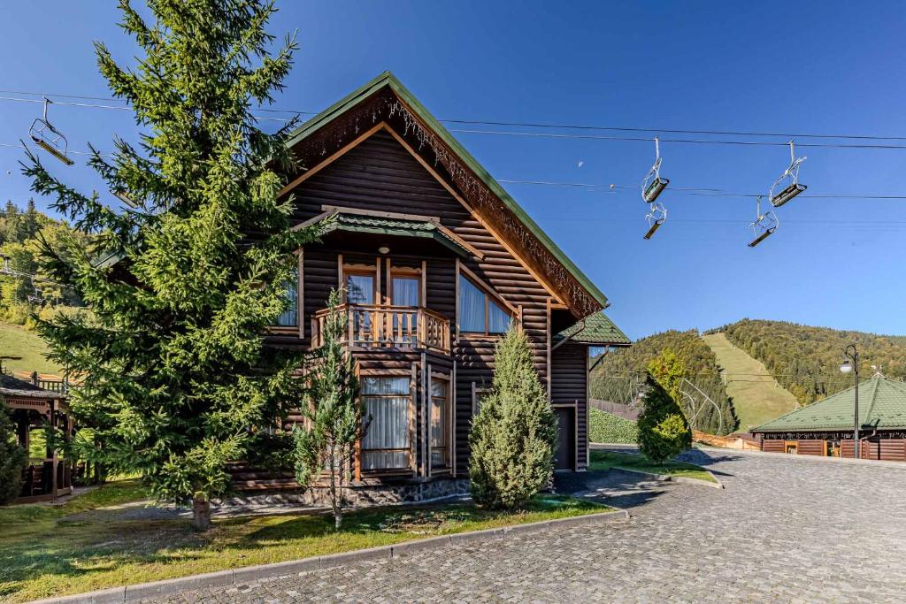 a log house with a porch and a balcony at Bukovel Hotel in Bukovel