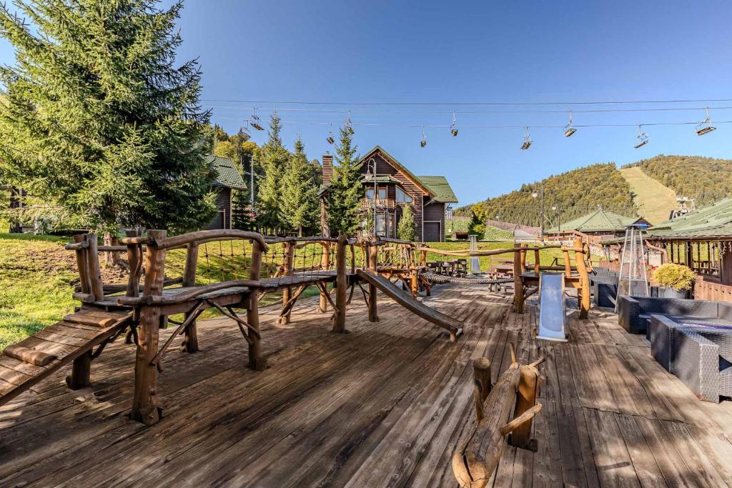 a wooden deck with a playground with benches at Bukovel Hotel in Bukovel