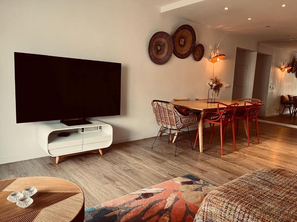 un salon avec une télévision et une table avec des chaises dans l'établissement T3 pièces lumineux à à 1 min de la plage Quartier Palm Beach Cannes, à Cannes