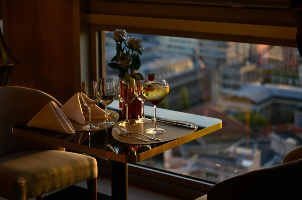 a table with two glasses of wine and a window at Grand Hotel Bucharest in Bucharest