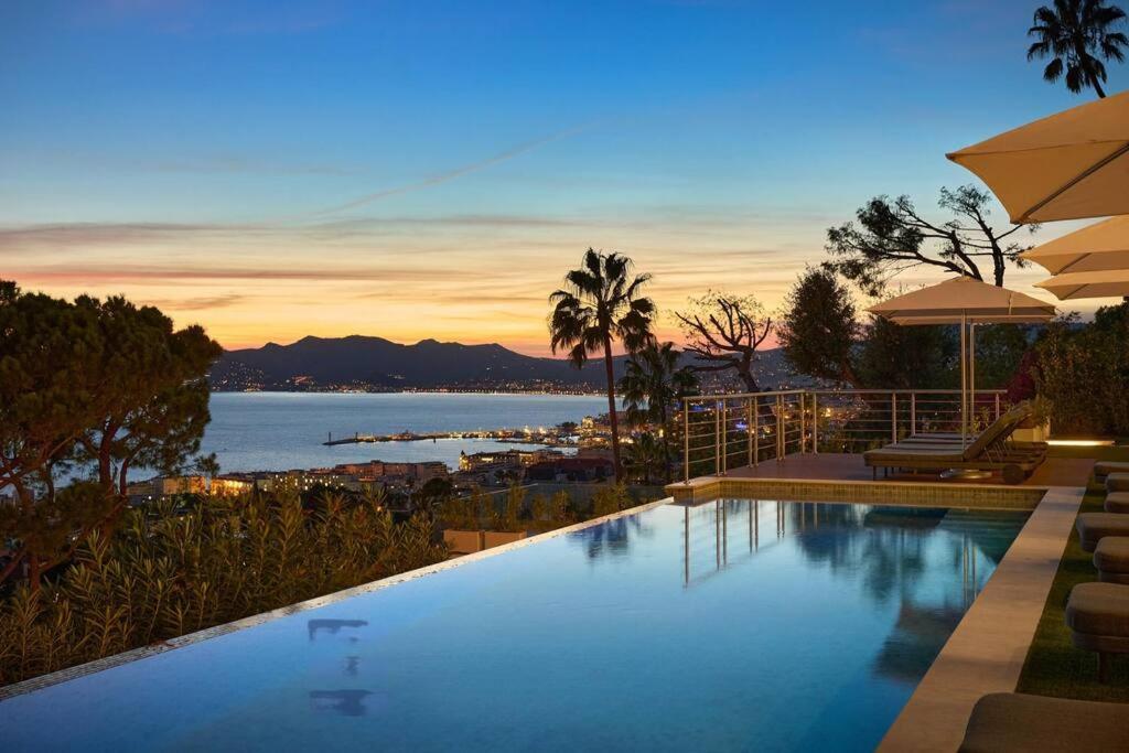 - une piscine avec vue sur l'océan au crépuscule dans l'établissement Cannes villa 6 chambres - Elisabeth, à Cannes