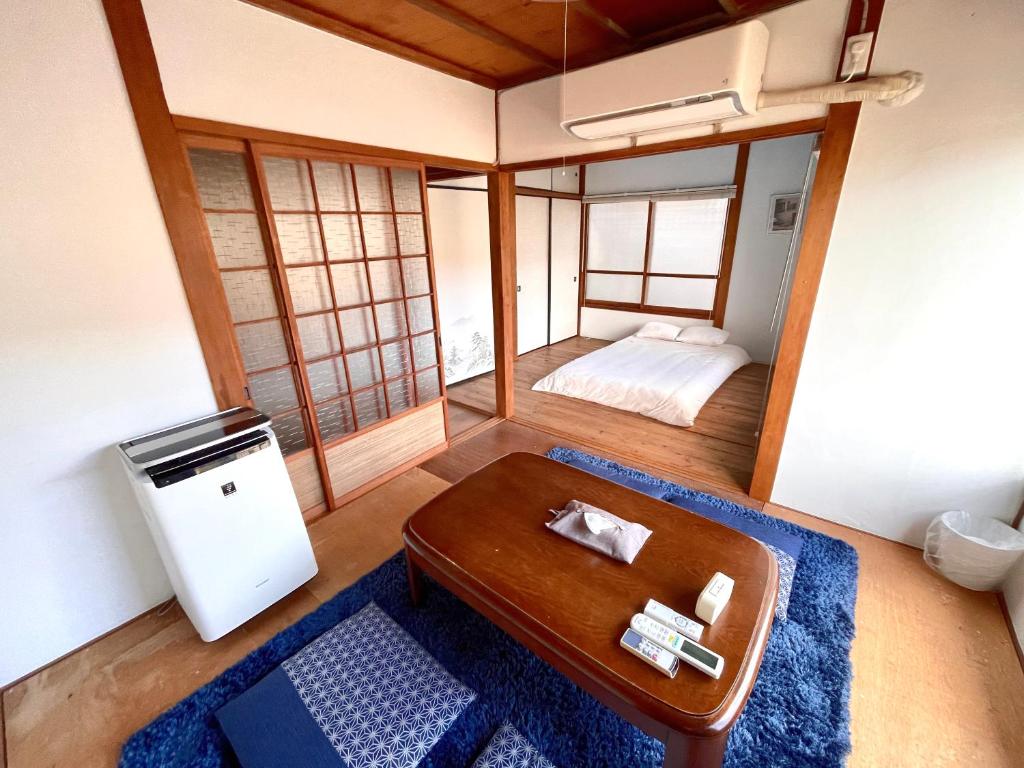 a room with a table and a bed in a room at BLUE HOUSE - Traditional Home - 5min, Beach, Bus, Train in Beppu