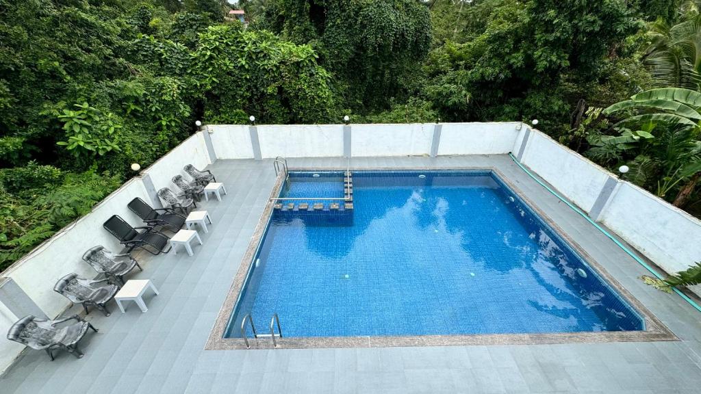 an overhead view of a swimming pool with tables and chairs at Golden Pearl Resort By Gemstone Hospitality in Alibag