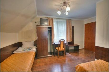 Room with two single beds, a desk, and a window with curtains.