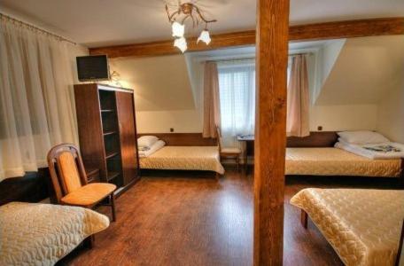 Room with three single beds, wooden furniture, and a ceiling light fixture.