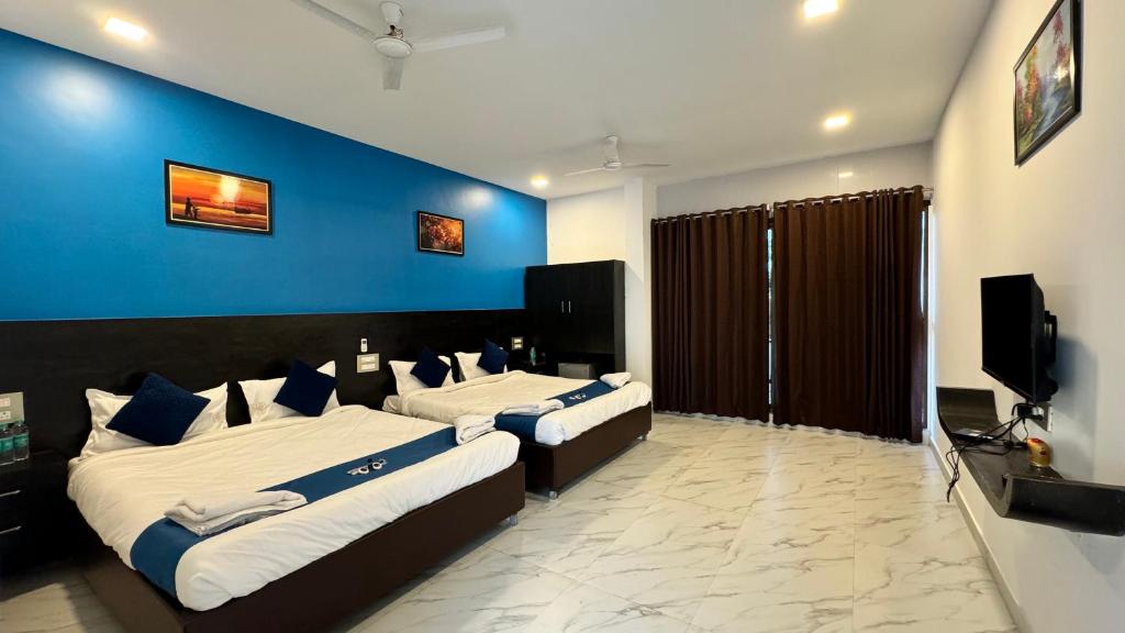 a bedroom with two beds and a blue wall at Golden Pearl Resort By Gemstone Hospitality in Alibag
