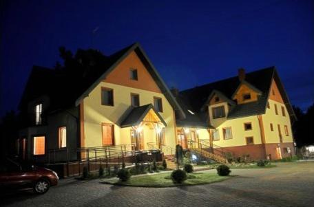 Large house illuminated at night, with multiple gables and a paved driveway.