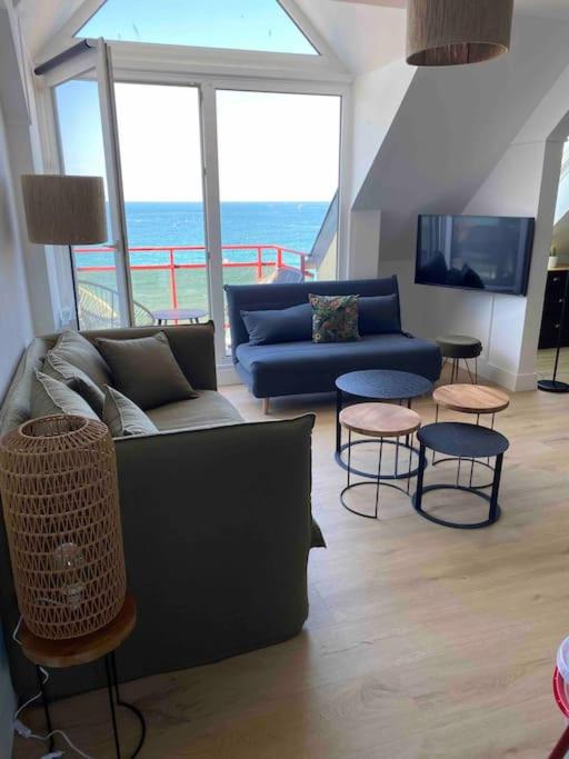 un salon avec un canapé et deux tables et chaises dans l'établissement Superbe appartement vue mer, à Perros-Guirec