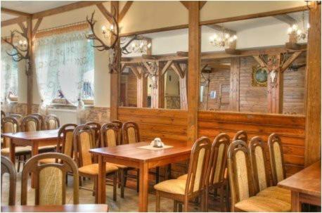 Rustic dining area with wooden tables, chairs, and decorative antler accents.