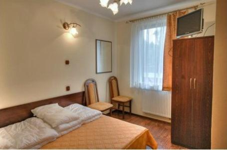 Room featuring a double bed, wooden wardrobe, chairs, and a wall-mounted TV.