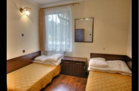 Cozy room with two single beds, wooden furniture, and a window with sheer curtains.