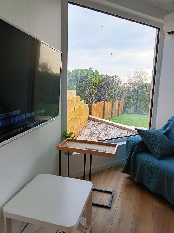 un salon avec une grande fenêtre et un canapé dans l'établissement Appart en RDC Confort-modernité-luminosité, à Palavas-les-Flots