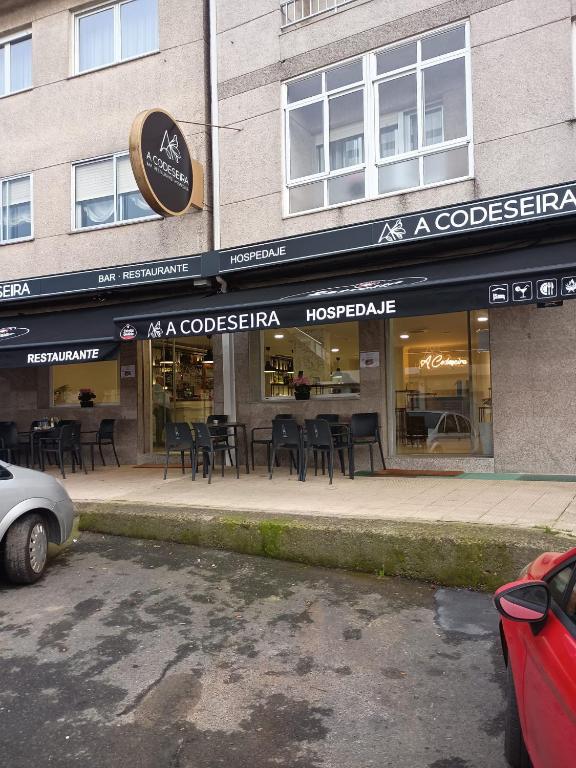 a store with tables and chairs in front of a building at Pensión A Codeseira Melide in Melide