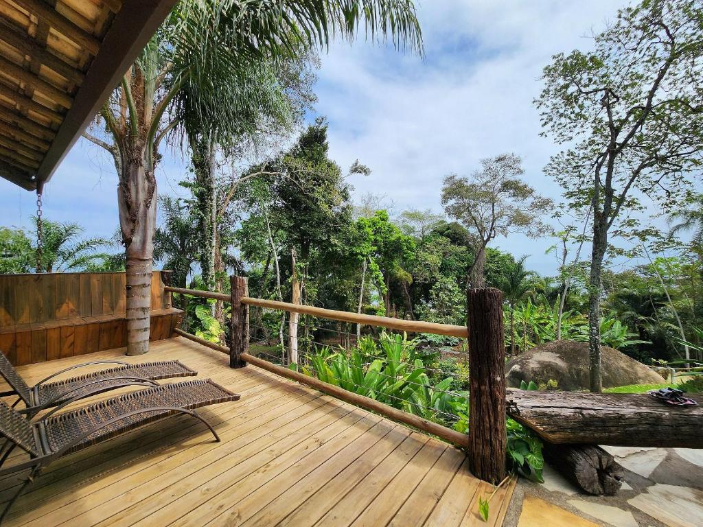 ein Holzdeck mit einem Stuhl und einem Elefanten im Hintergrund in der Unterkunft Bangalô com vista e piscina natural em Flechas in Ilhabela