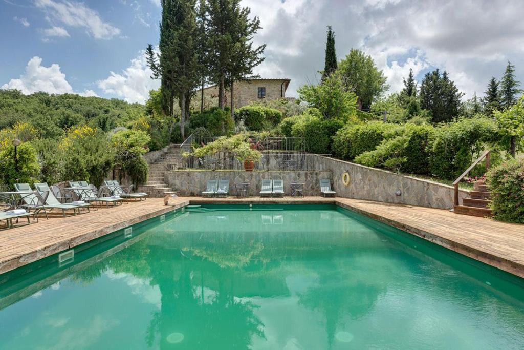 a swimming pool with chairs and a house at AMORE RENTALS - Villa Il Casello in Greve in Chianti