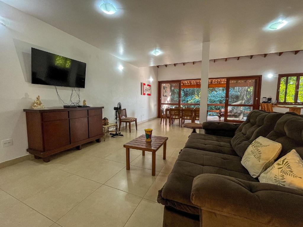 a living room with a couch and a flat screen tv at Casa espaçosa Ilhabela perto da praia das Conchas in Ilhabela