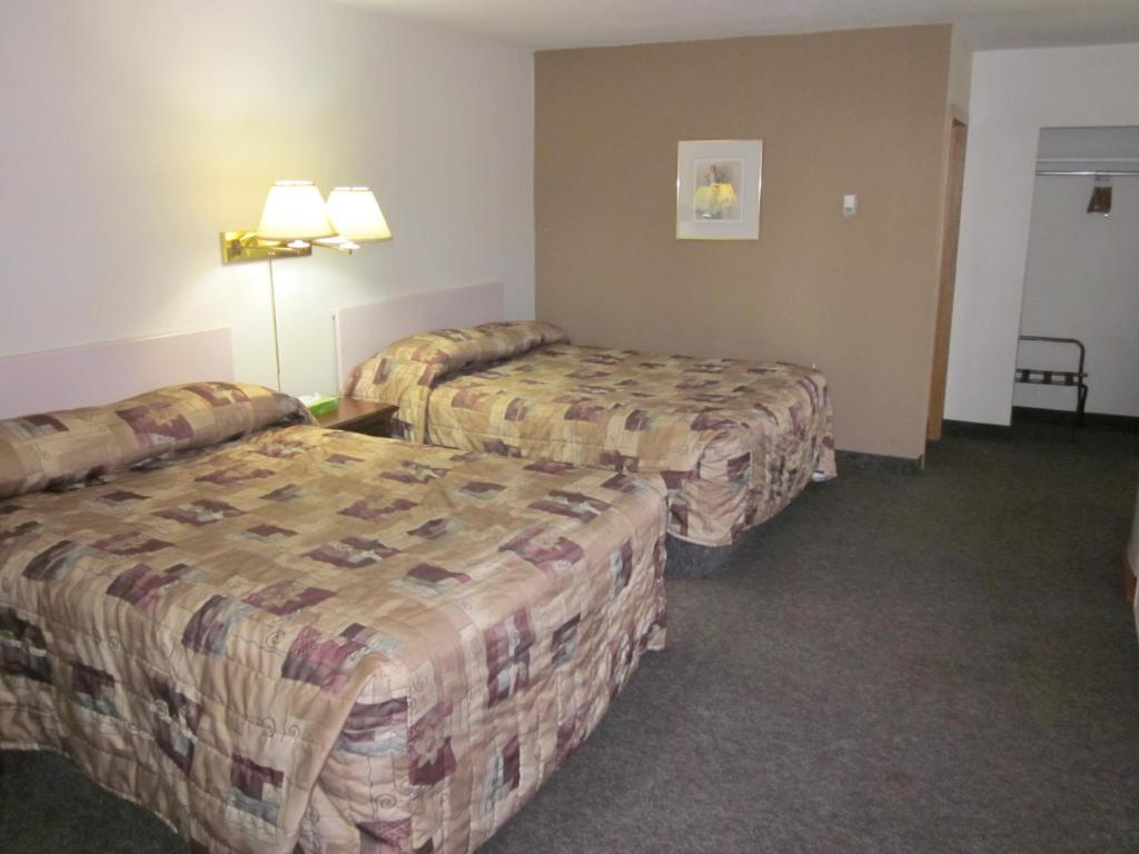 a hotel room with two beds and a table at Chinook Motel in Lethbridge