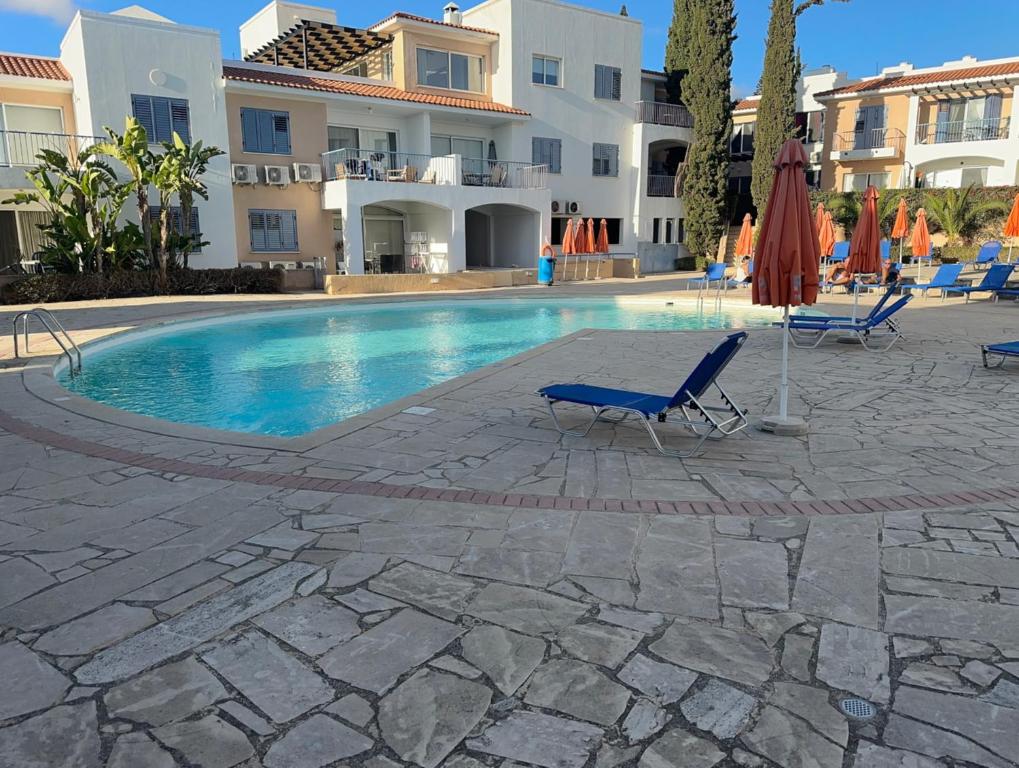 a swimming pool with two chairs and an umbrella at Peyia Spring in Peyia